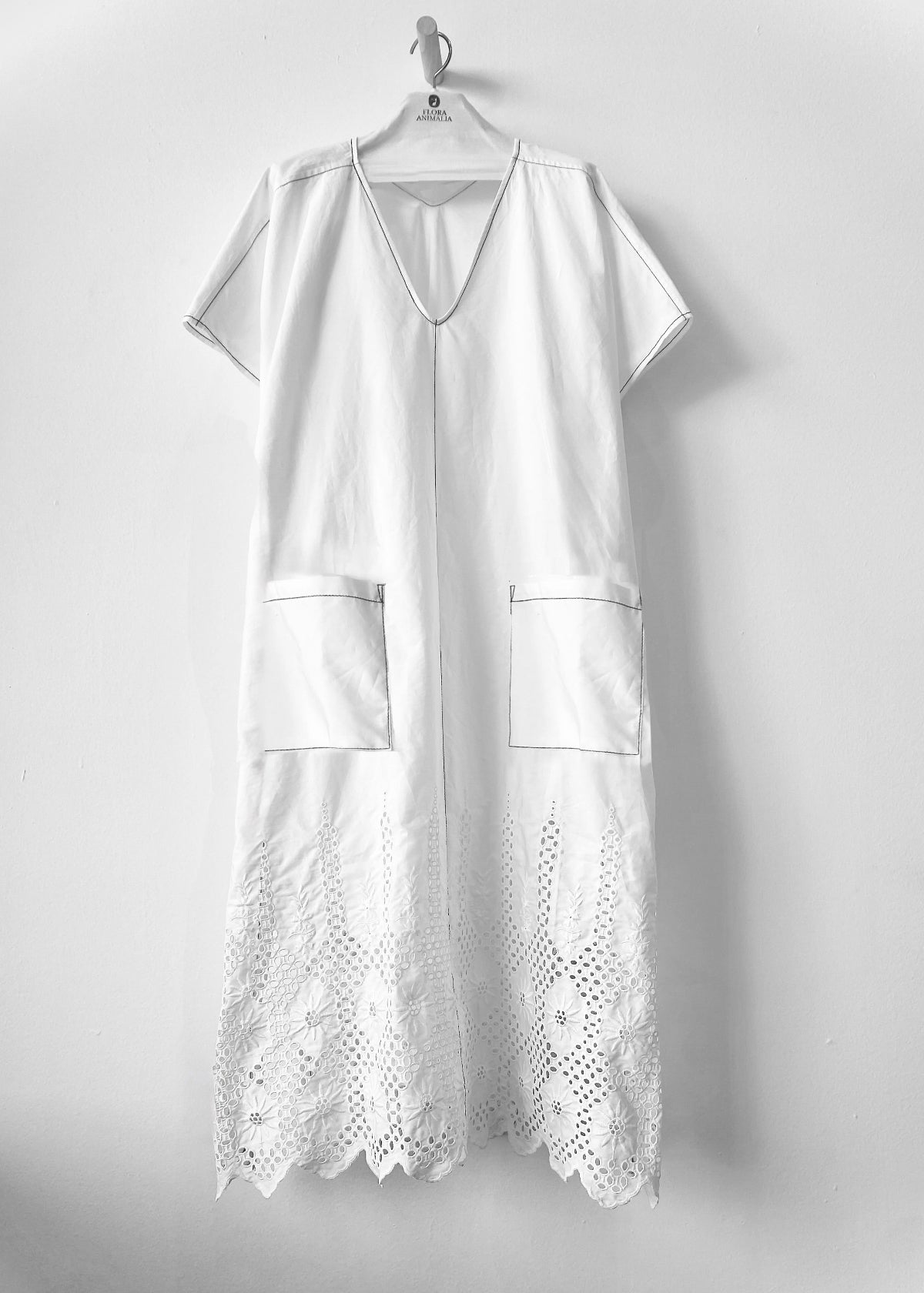 White dress with eyelet details on a hanger against a white background
