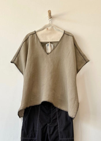 khaki top with black pants on a hanger against a white background