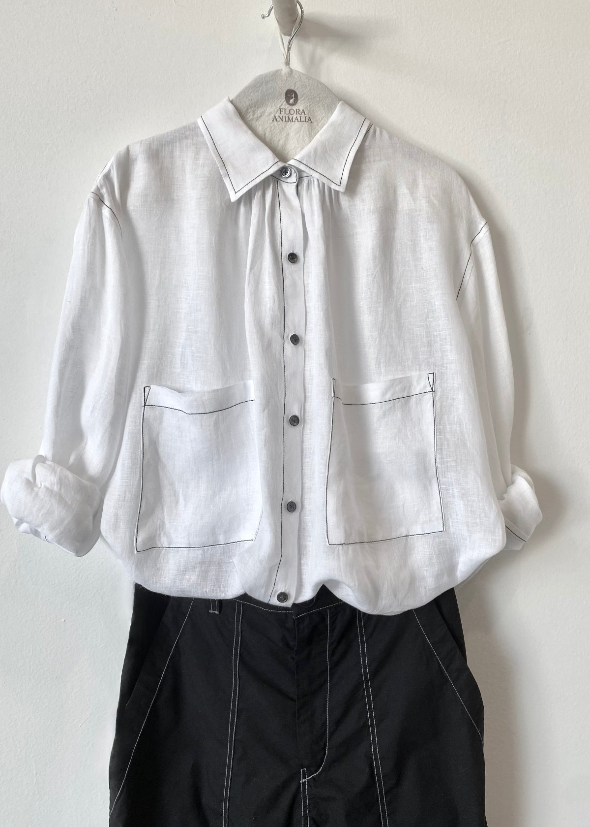 White shirt with rolled-up sleeves on a hanger against a white background