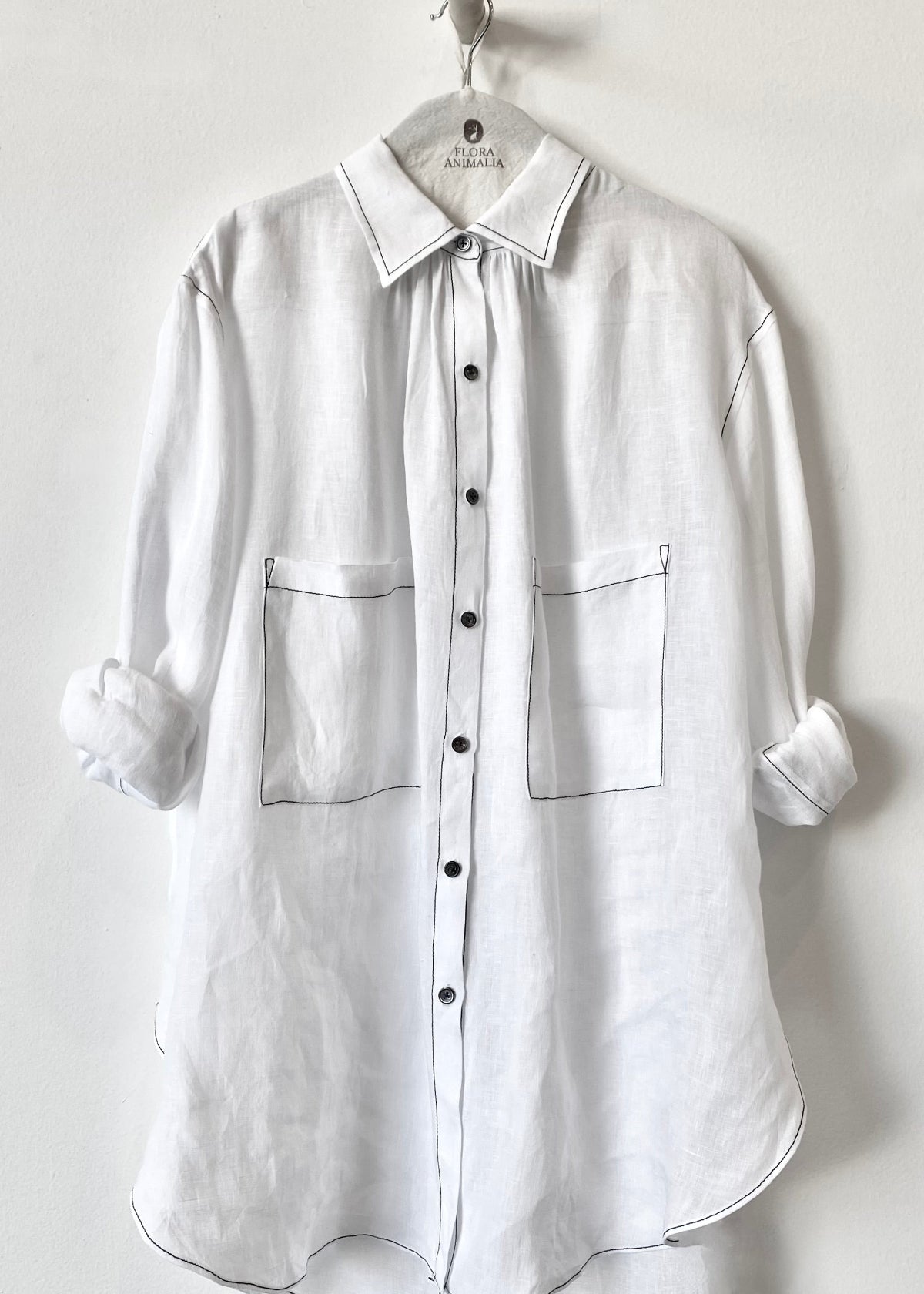 White shirt with rolled-up sleeves on a hanger against a white background