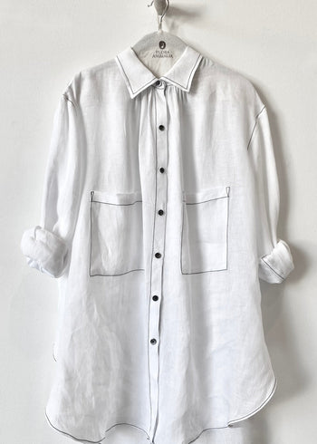 White shirt with rolled-up sleeves on a hanger against a white background