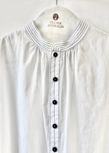 close up of White shirt with black buttons on a hanger with 'Flora Animalia' label.