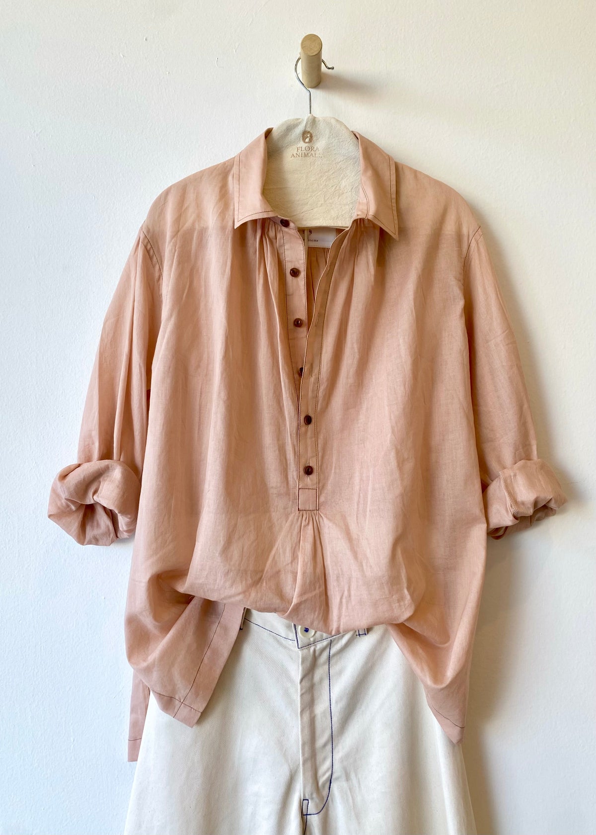 Pink shirt on a hanger against a white wall