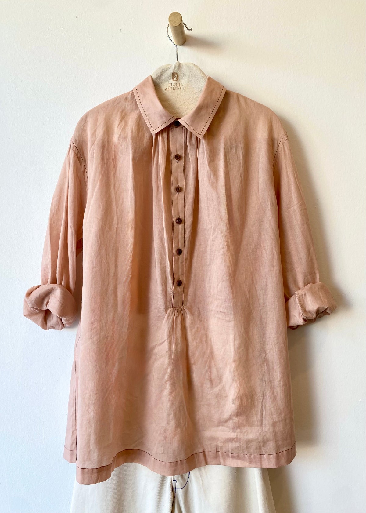 Pink shirt on a hanger against a white wall