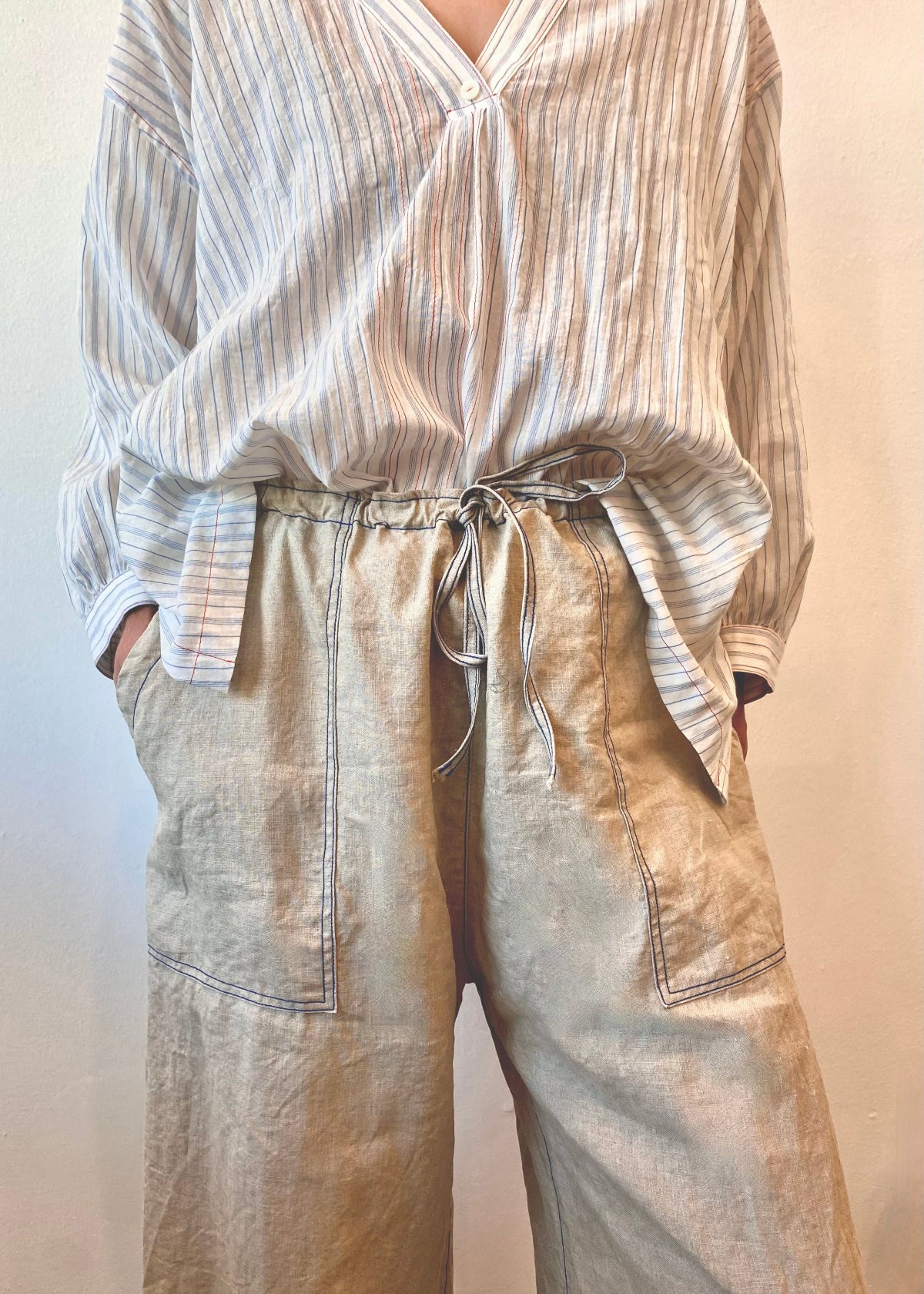 Striped shirt and beige drawstring pants on a plain background