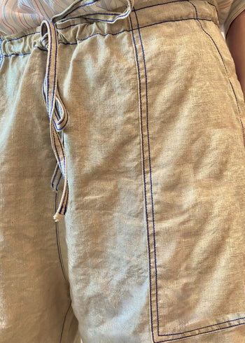Close-up of beige pants with a drawstring waistband and patch pocket