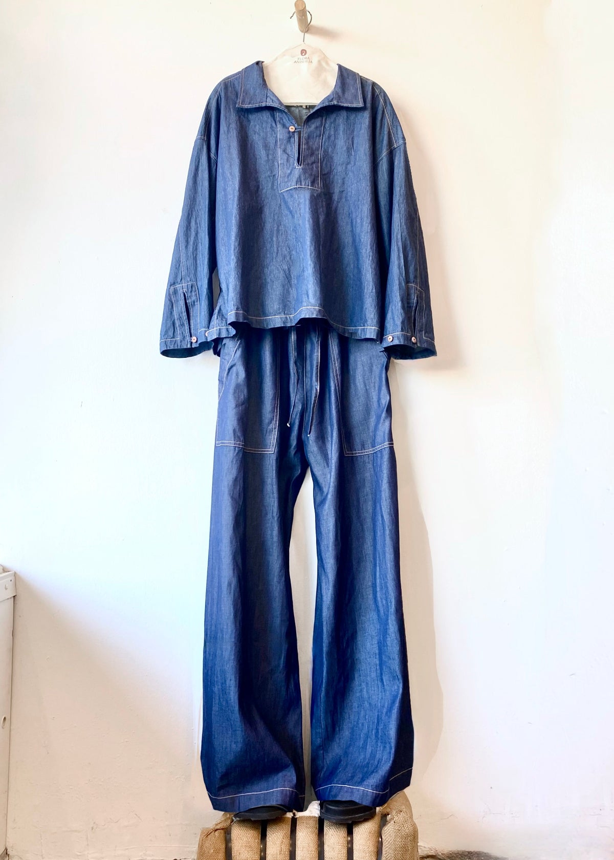 Blue denim top and pants hanging on a white wall