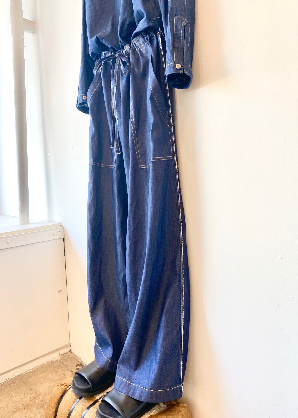 Blue denim top and pants hanging on a white wall