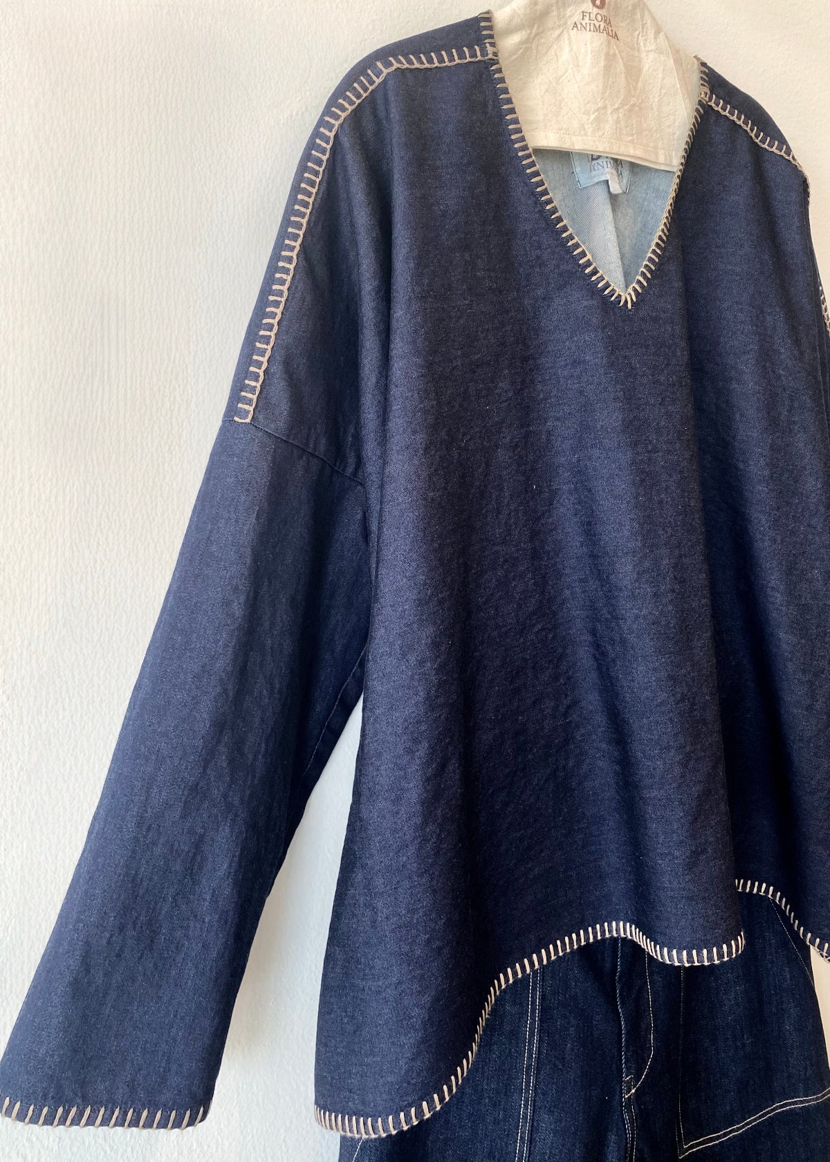 Navy blue denim Praia top with jeans on a hanger against a white background