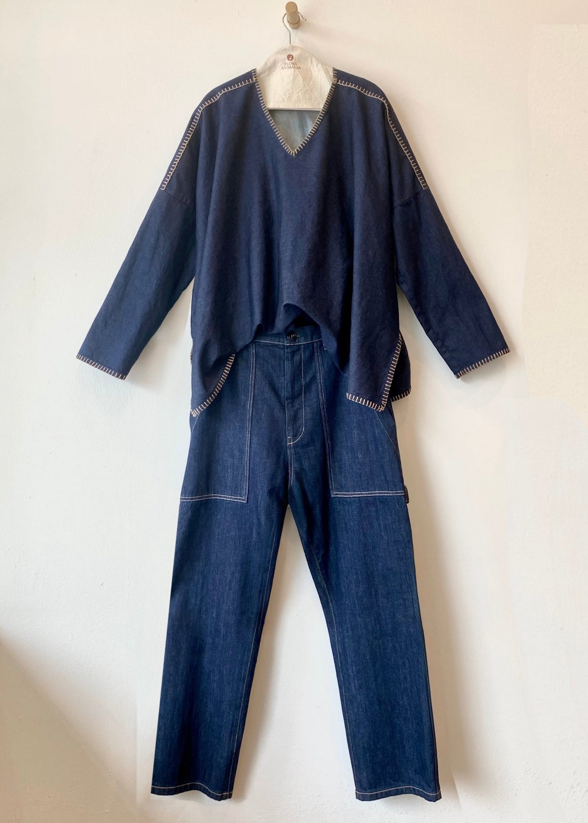 Blue denim outfit with v-neck top and pants on a white background