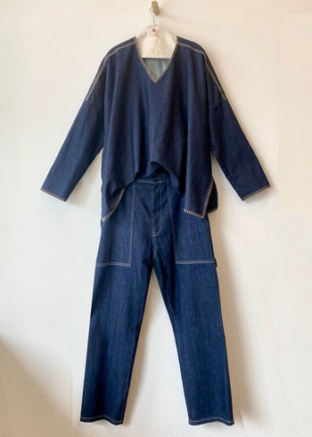 Blue denim outfit with v-neck top and pants on a white background