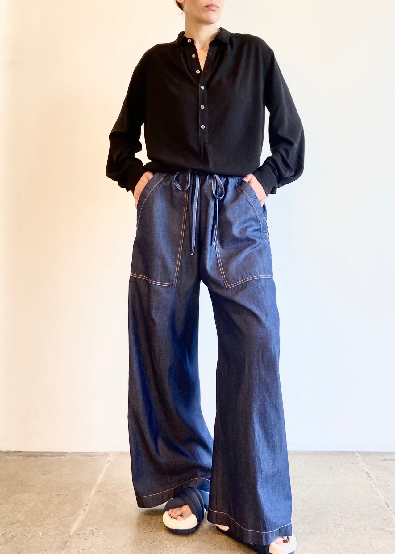 Person wearing a black Agnes shirt and Picker's blue jeans against a plain background