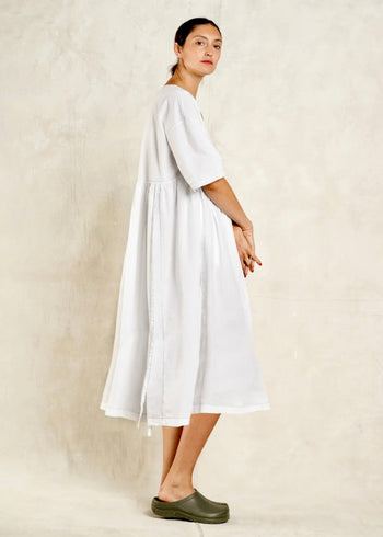 Woman wearing a white dress standing against a plain background