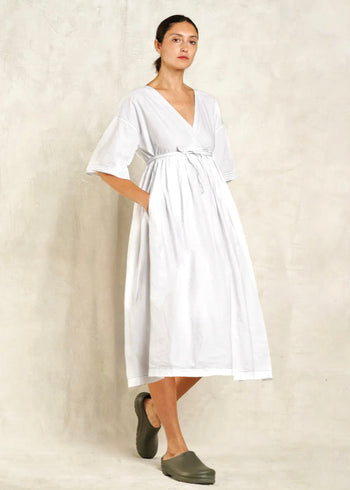 Woman wearing a white dress with a plain background