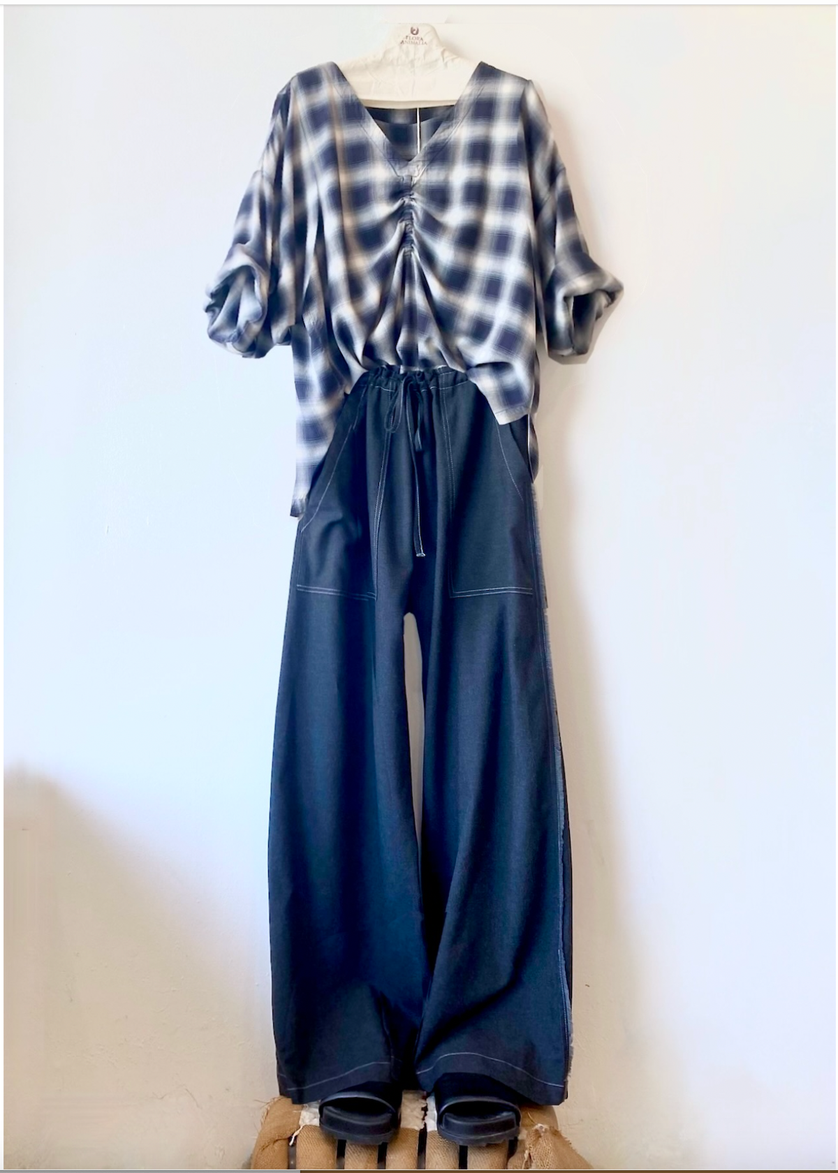 Plaid shirt and navy wide-leg pants on a hanger against a white background