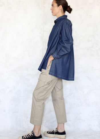 side view denim loose top with beige pants agains neutral color background