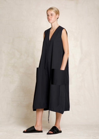 Woman wearing a black sleeveless dress against a neutral background