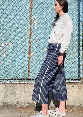 blue and white striped denim cropped drawstring pants with white button down top. side view