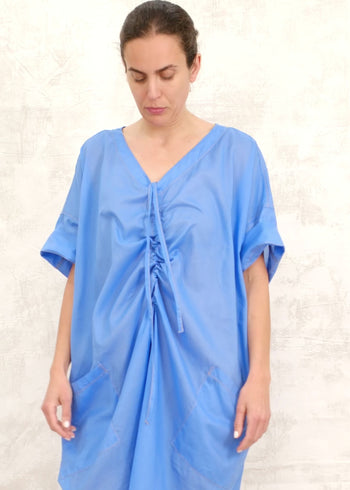 woman demonstrating the pullstring on a blue dress
