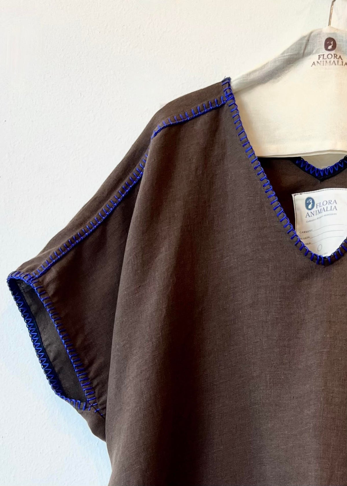 Brown poncho with blue trim on a hanger against a white background